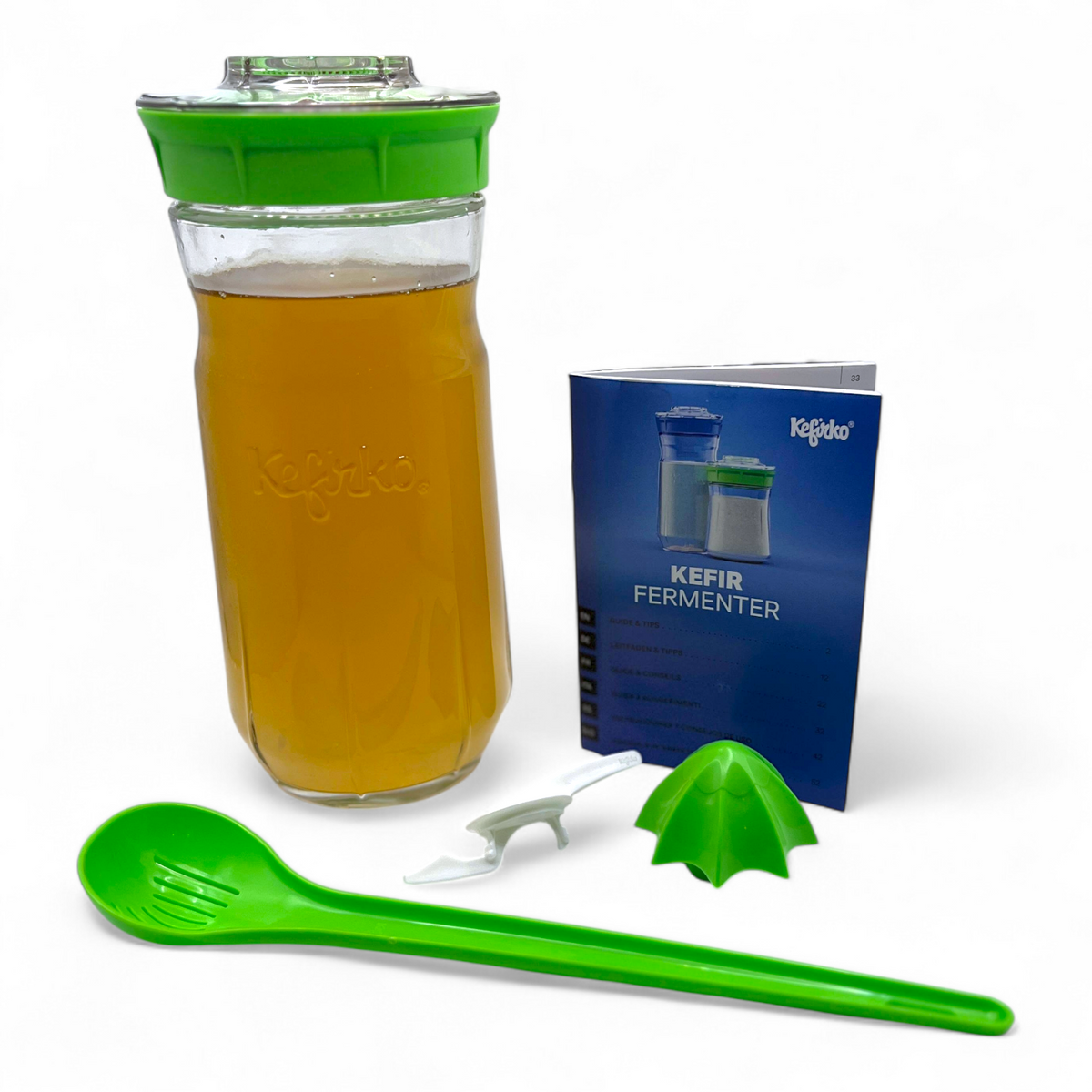 Large green Kefirko kit with water kefir grains, green spoon, and blue manual on a white background