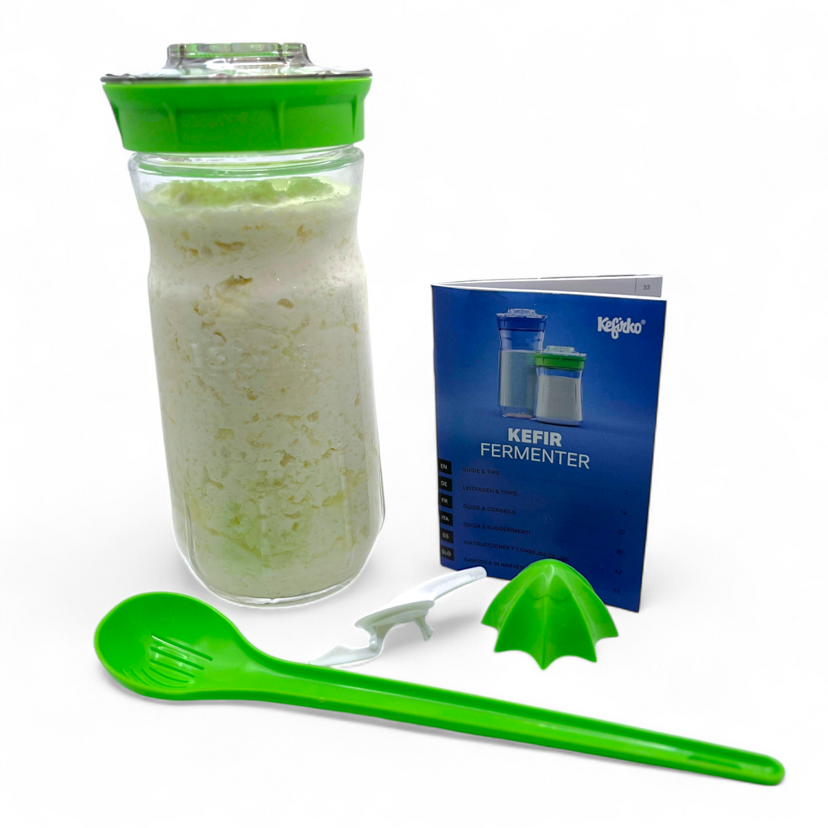 Large green Kefirko starter kit with milk kefir grains, glass jar, green spoon, and blue manual on a white background
