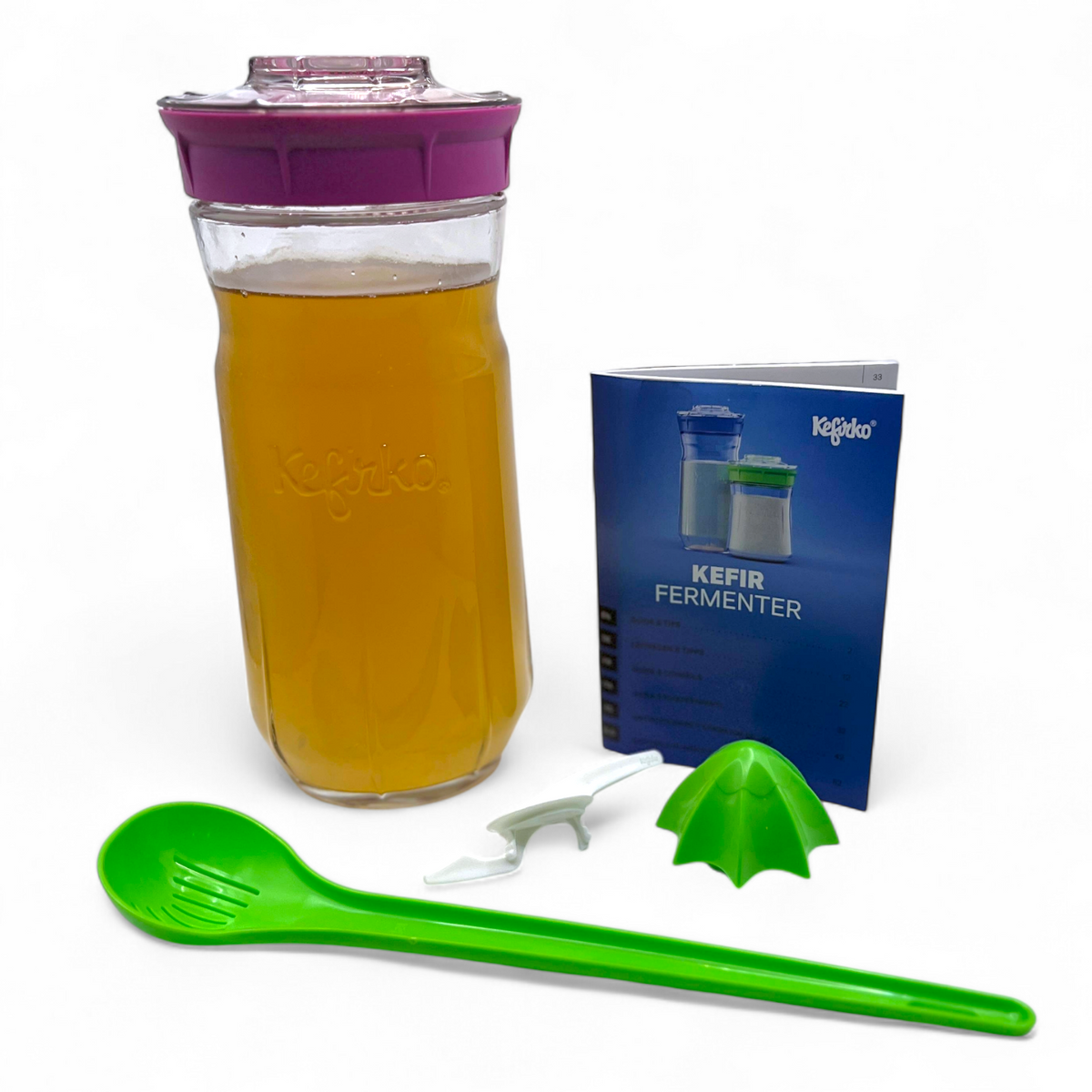 Large pink Kefirko kit with water kefir grains, green spoon, and blue Kefir Fermenter book on a white background