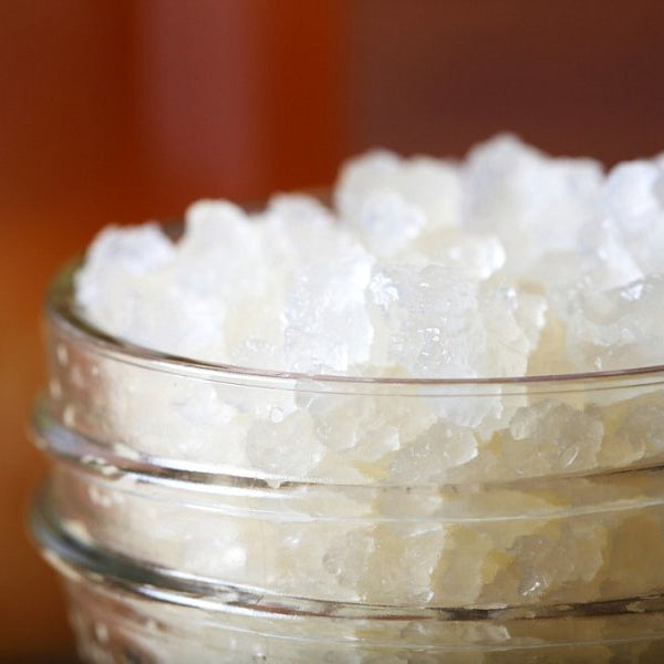 Glass jar filled up with water kefir grains close up with jar of water kefir in background.