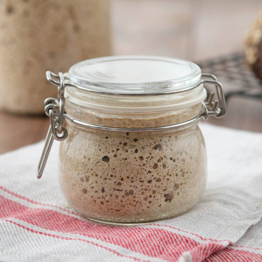 Wholegrain wheat sourdough starter in a glass jar, naturally fermented for homemade artisan bread.