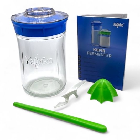 Kefir maker kit with clear container, blue lid, green straws, and a booklet on a white background